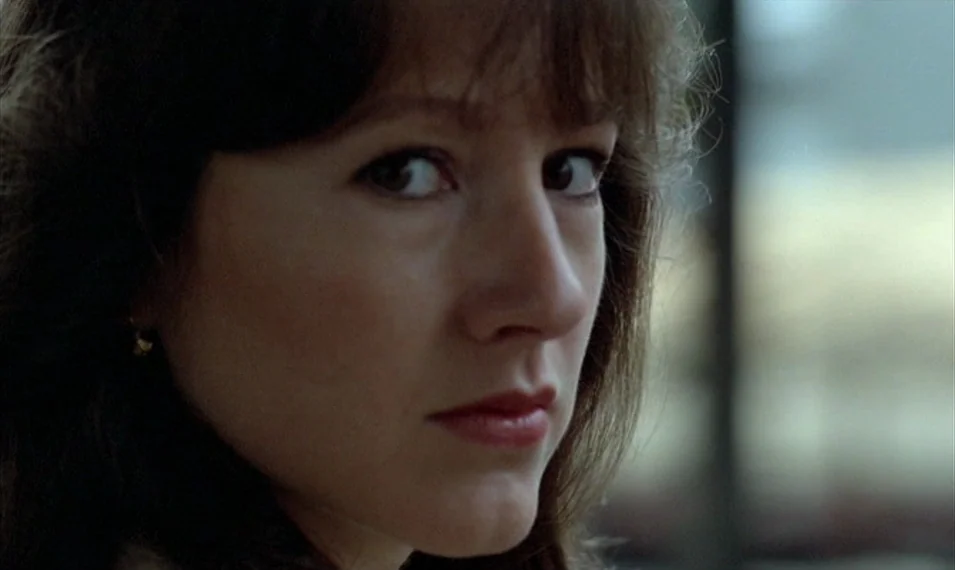 Every Man for Himself (1980) movie still: closeup — A close-up shot of a woman with dark wavy hair in a room. She turns her head to look directly…
