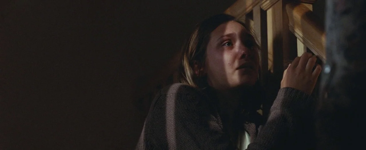 Martha Marcy May Marlene (2011) movie still: closeup — A dimly lit staircase features dark wooden railings and shadow-filled corners at night. A…