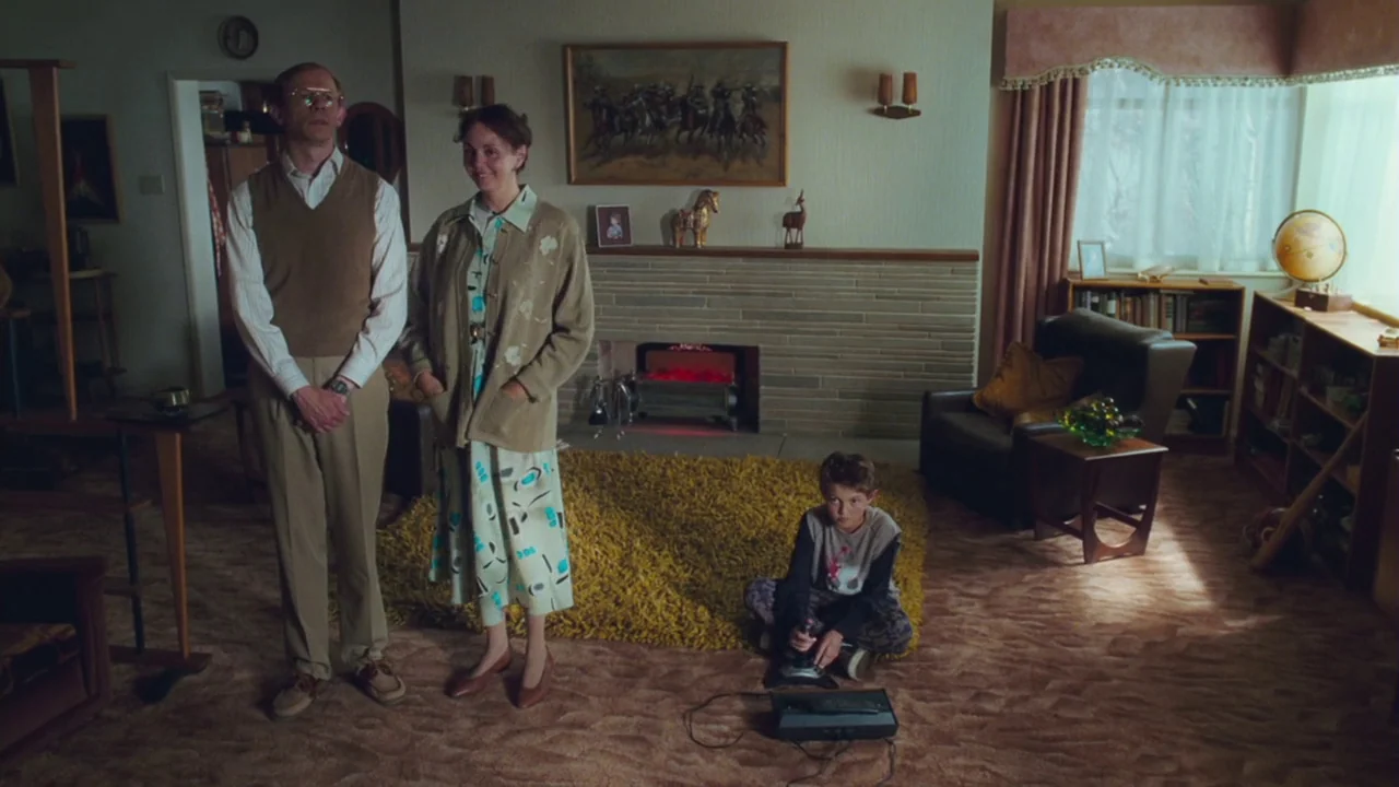 Charlie and The Chocolate Factory (2005) movie still: fullbody — A 1980s living room features a textured stone fireplace, patterned carpet, and…