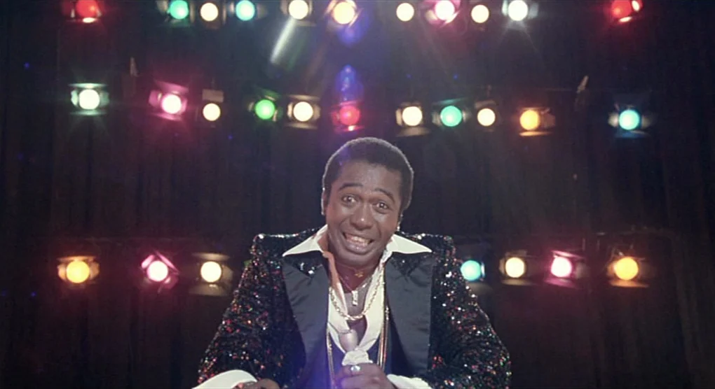 All That Jazz (1979) movie still: medium — A dark concert venue with rows of multi-colored spotlights mounted on the back wall. An entertainer…