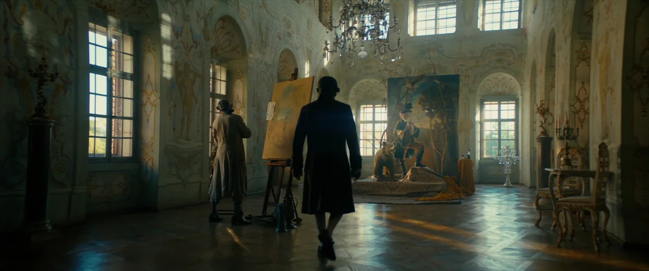The Promised Land (2023) movie still: fullbody — A spacious, high-ceilinged room features decorative muraled walls and large arched windows with…