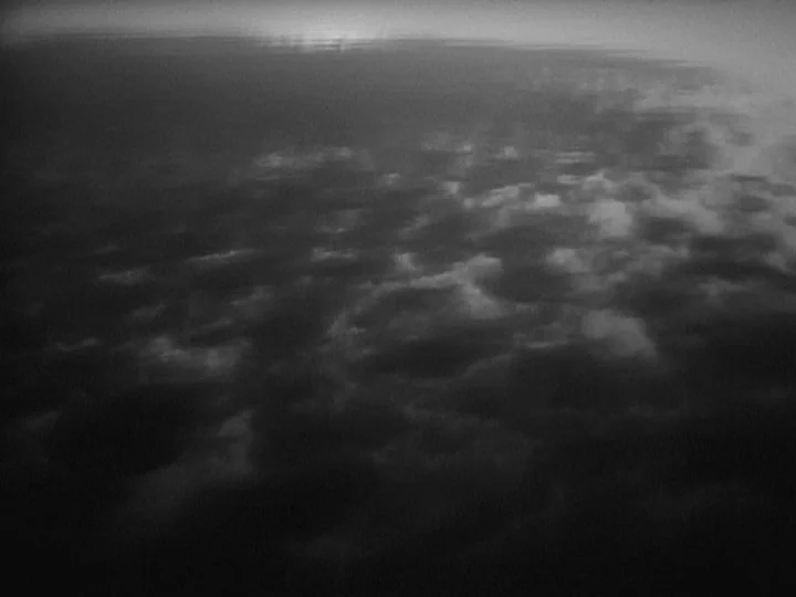 Through A Glass Darkly (1961) movie still: establishing — A dark, overcast sky with textured cloud layers fills the frame. Light reflects faintly on…