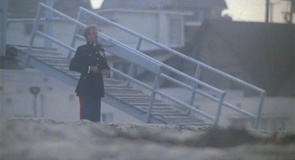 Coming Home (1978) movie still: fullbody — A sandy coastal environment features a weathered lifeguard tower structure with steep wooden stairs. A…