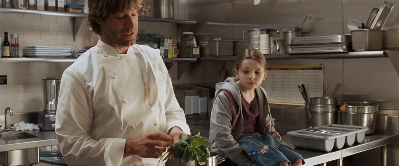 No Reservations (2007) movie still: medium — A professional kitchen features stainless steel surfaces, wire shelving, and various culinary prep…