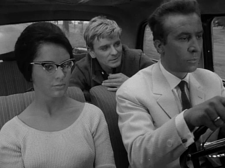 Knife In The Water (1962) movie still: medium — A man drives a car with a woman in the passenger seat and another man behind them. The interior is…