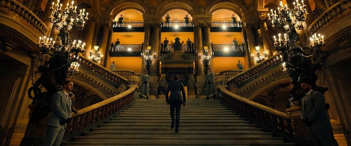 John Wick: Chapter 4 (2023) movie still: wide — A grand opulent marble staircase in a neoclassical building with multiple tiered levels above. A man…