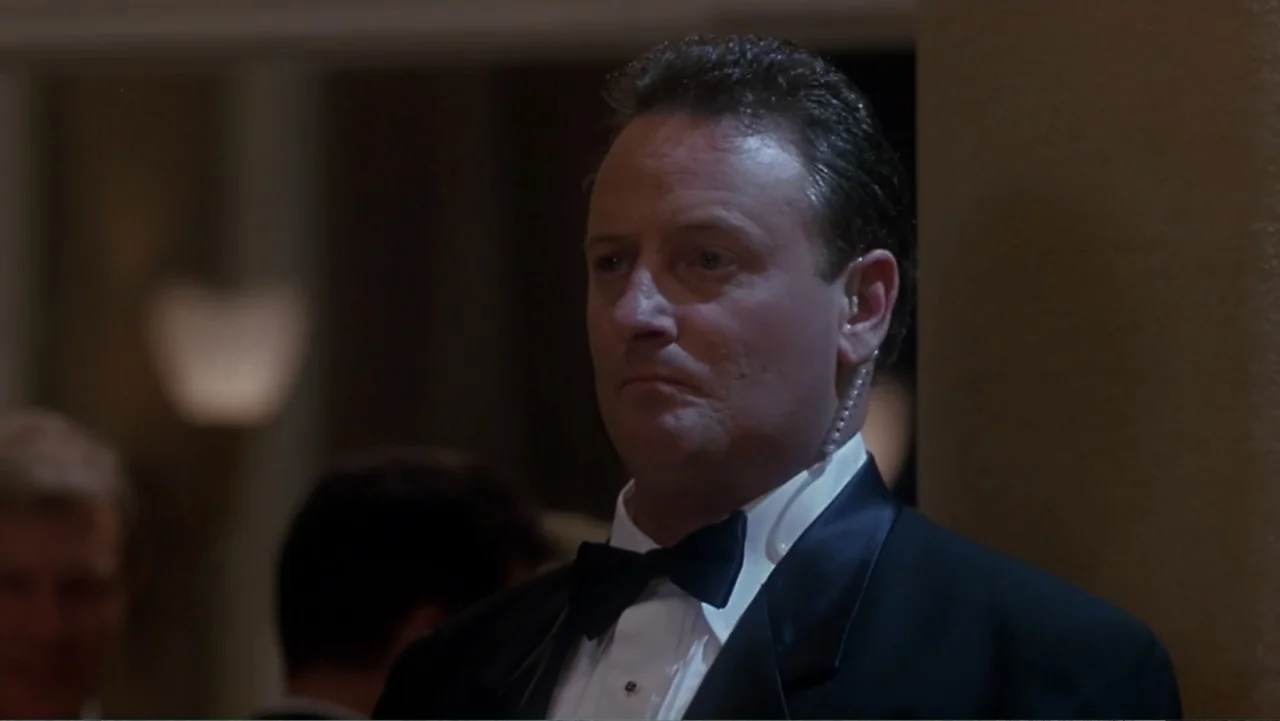 How to Lose a Guy in 10 Days (2003) movie still: medium — A dimly lit interior space with soft background blur from distant lamps. A middle-aged man…
