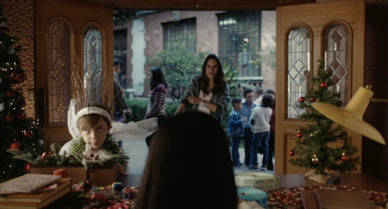 Dating Santa (2023) movie still: medium — A decorated interior space with a desk leads to an open doorway showing courtyard visitors. A young girl…