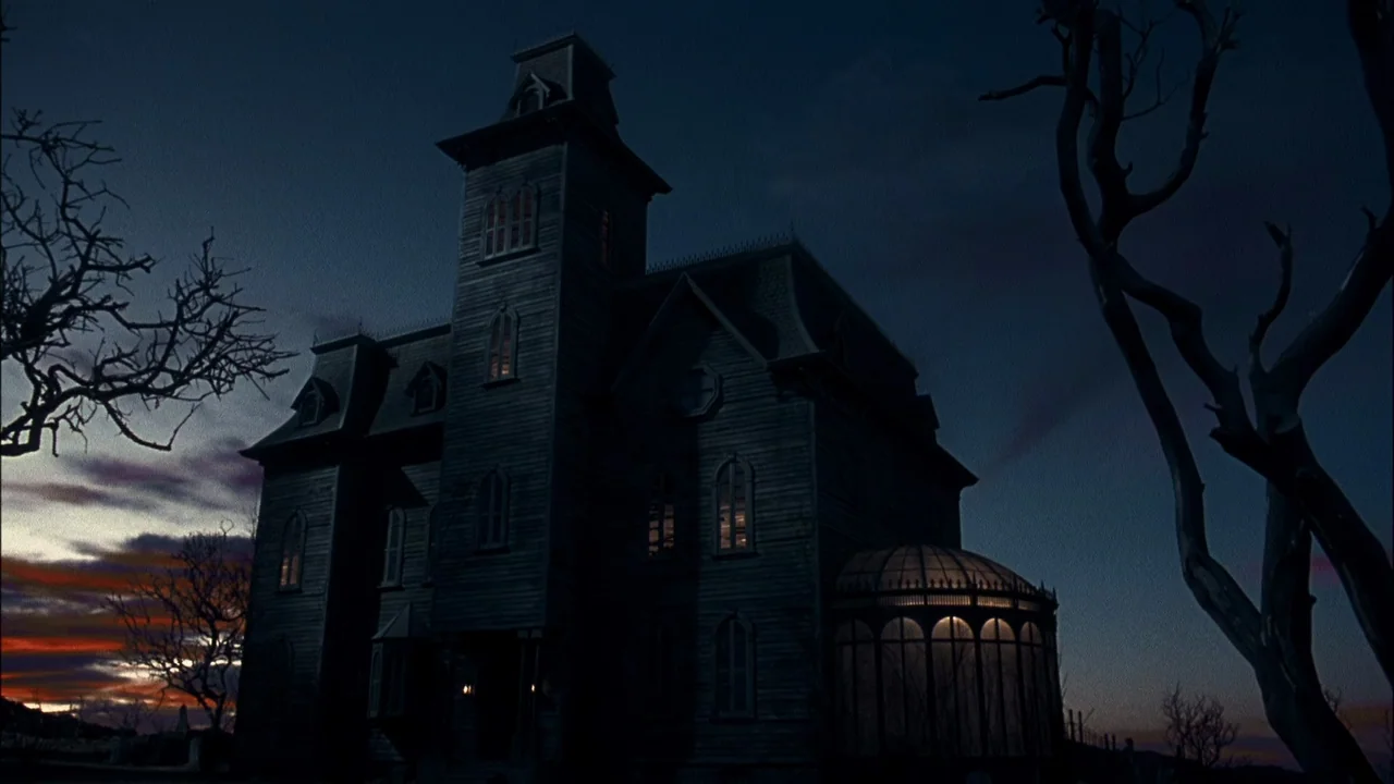 Addams Family Values (1993) movie still: establishing — A dark, multi-storied wooden house sits against a fading sunset at twilight. Bare, leafless…