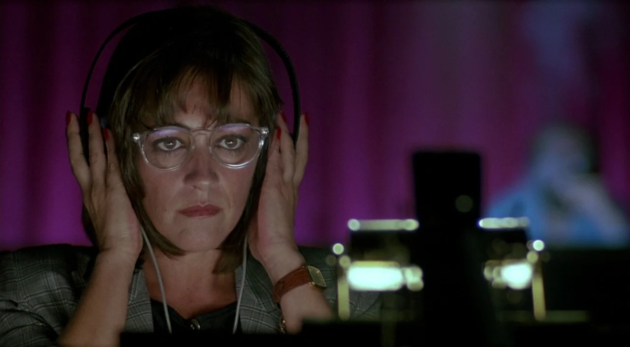 Women on the Verge of a Nervous Breakdown (1988) movie still: closeup — A dimly lit room with purple light cast against a curtain in the background.…