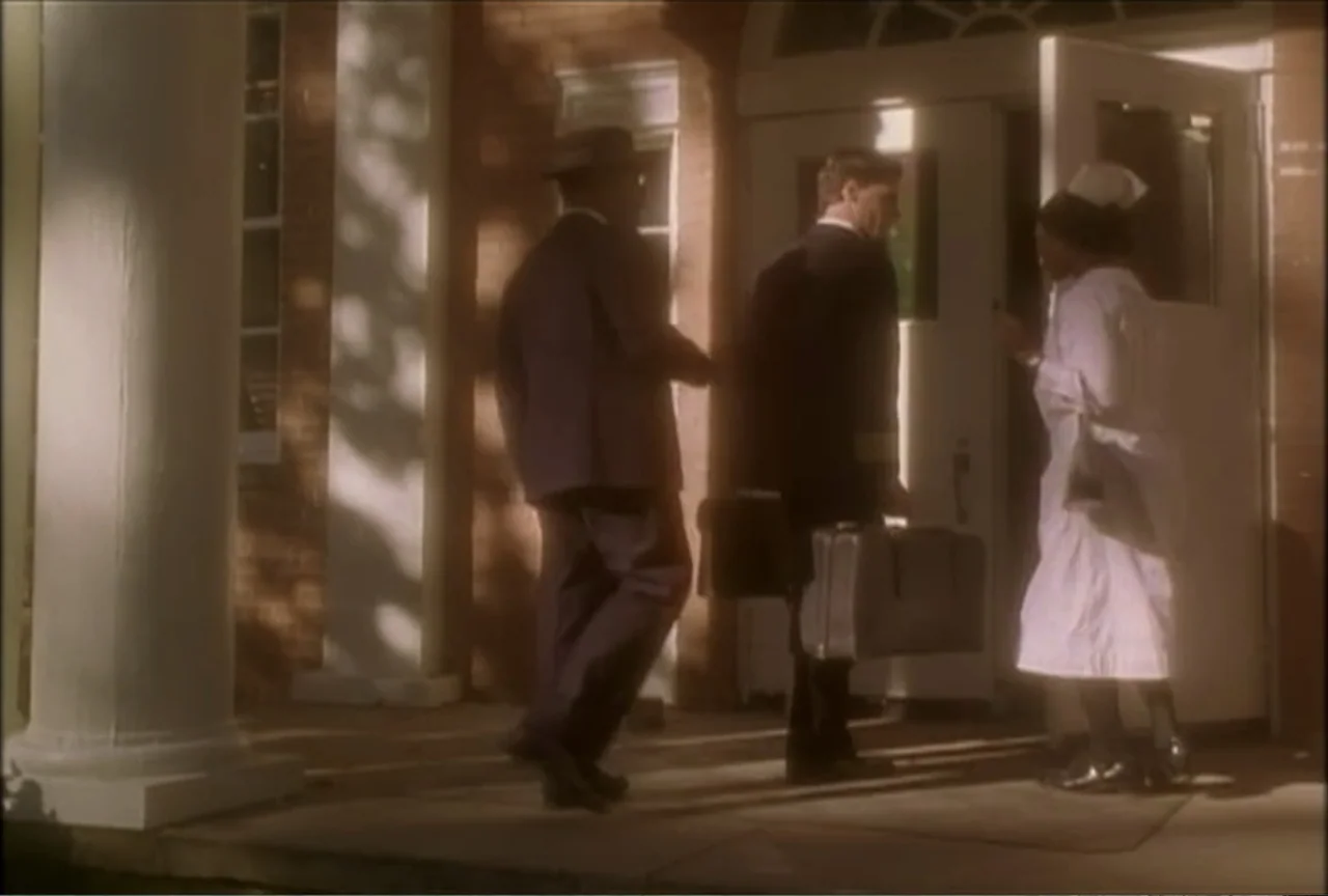 Miss Evers' Boys (1997) movie still: fullbody — A brick building with white pillars and an open front door serves as the setting. Two men carrying…