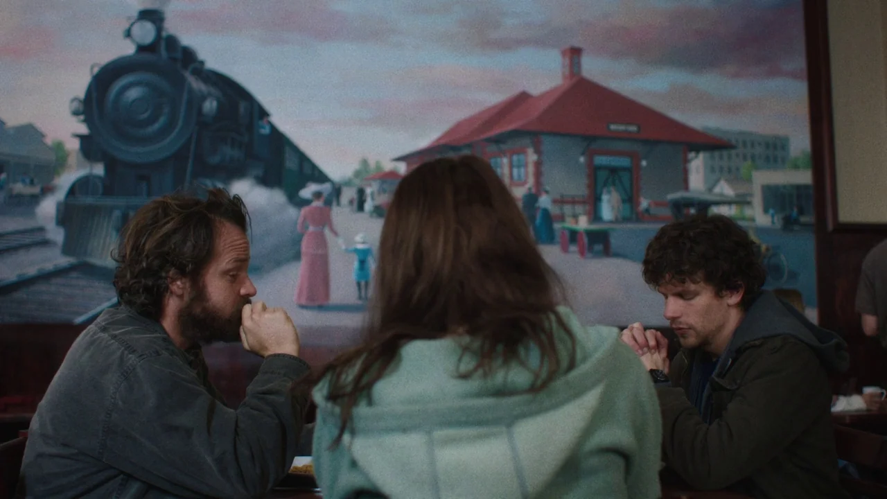 Night Moves (2013) movie still: medium — A restaurant booth with a large wall mural depicting a vintage train station scene. Three people sit at the…