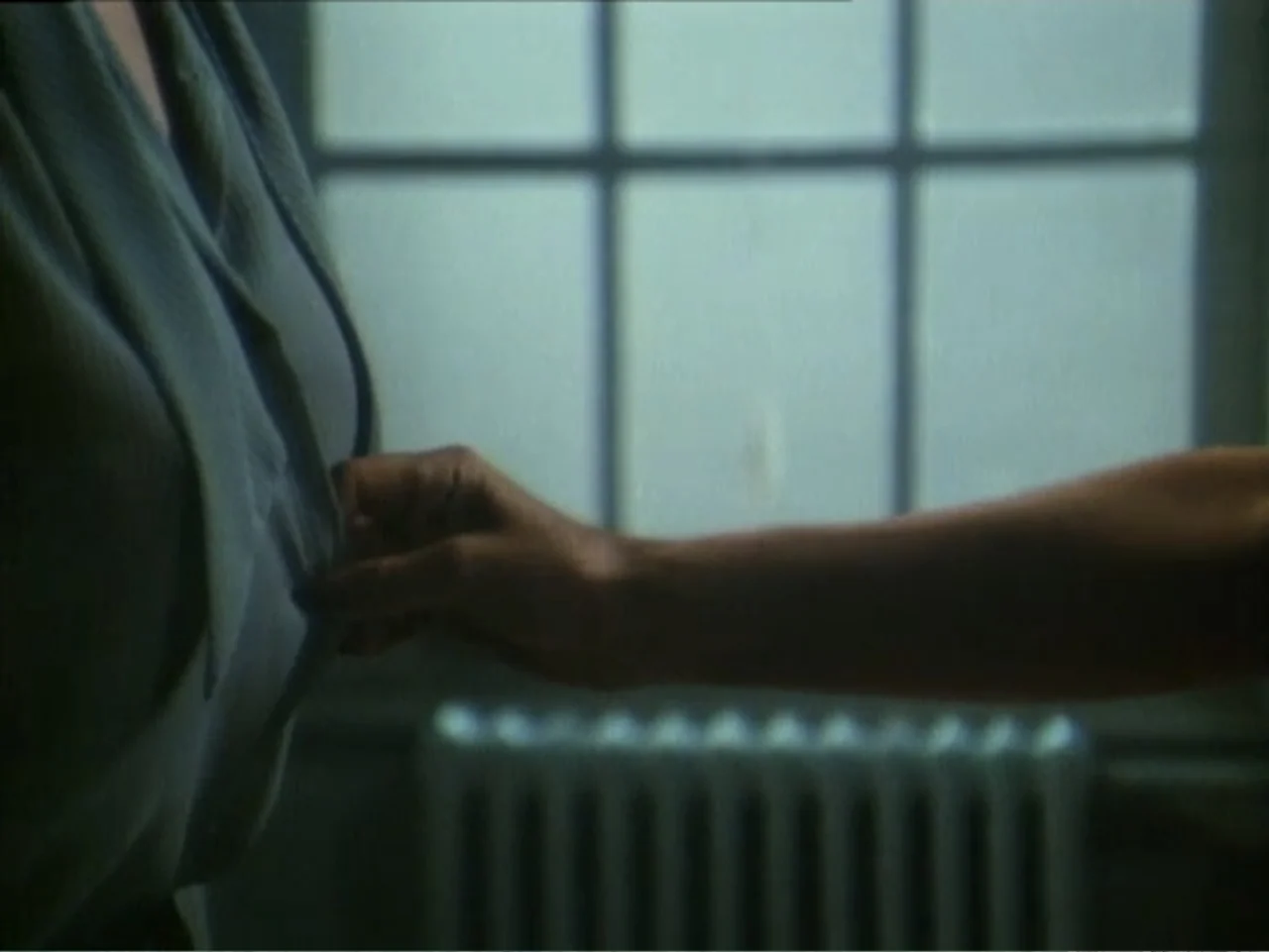 Curtains (1995) movie still: closeup — An interior space features a window with grid panes and a radiator below. A hand reaches across to touch the…