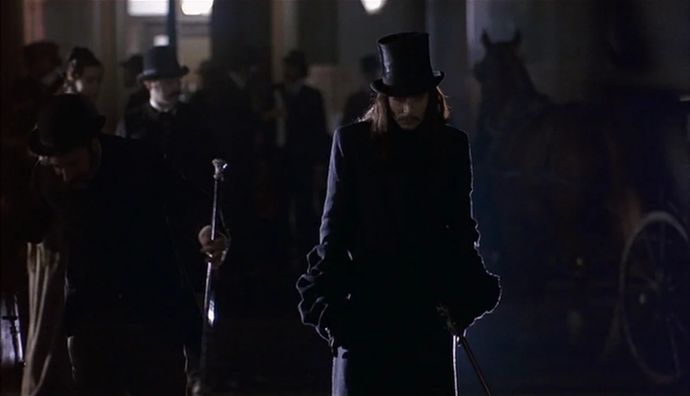 Bram Stoker’s Dracula (1992) movie still: medium — A dark, dimly lit 19th-century street scene at night featuring a horse carriage. Two men in…