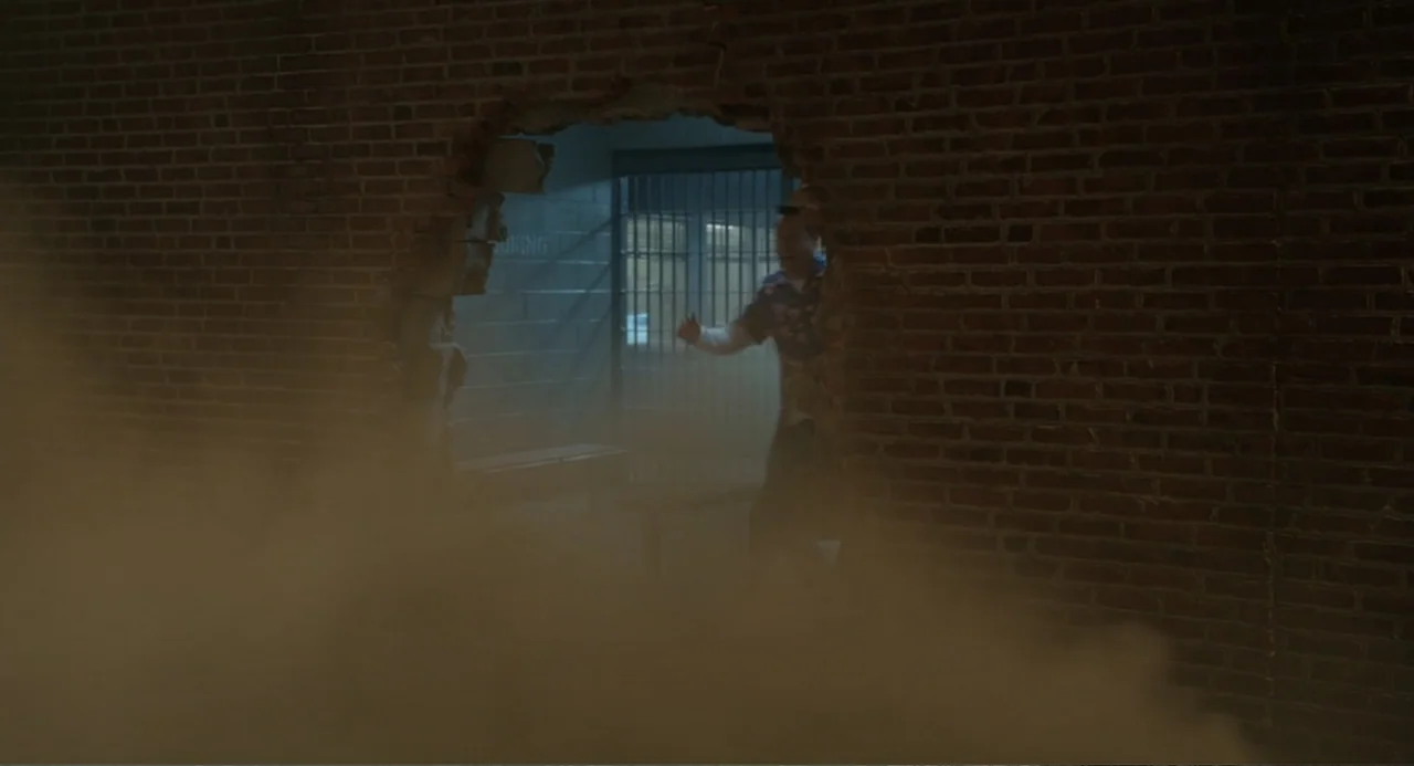 Harold and the Purple Crayon (2024) movie still: medium — A man steps through a jagged hole in a red brick wall. Dust clouds billow out into the…