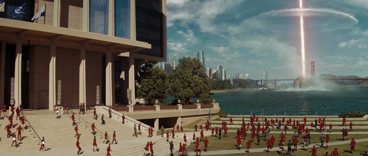 Star Trek (2009) movie still: establishing — A modern stone plaza faces a bay with a distant city skyline visible. A bright energy beam strikes the…