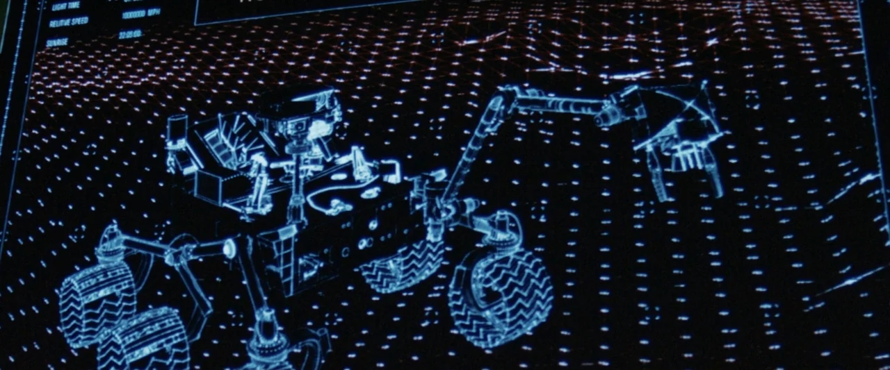 2036 Origin Unknown (2018) movie still: medium — A digital screen displays a blue wireframe 3D model of a lunar rover. The rover sits on a grid…