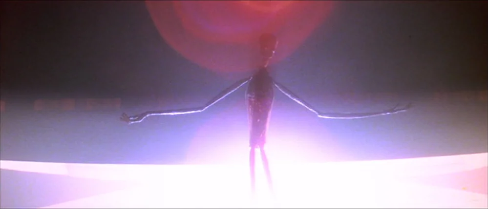 Close Encounters Of The Third Kind (1977) movie still: fullbody — An indistinct dark space lit by a singular, intense circular magenta light source.…