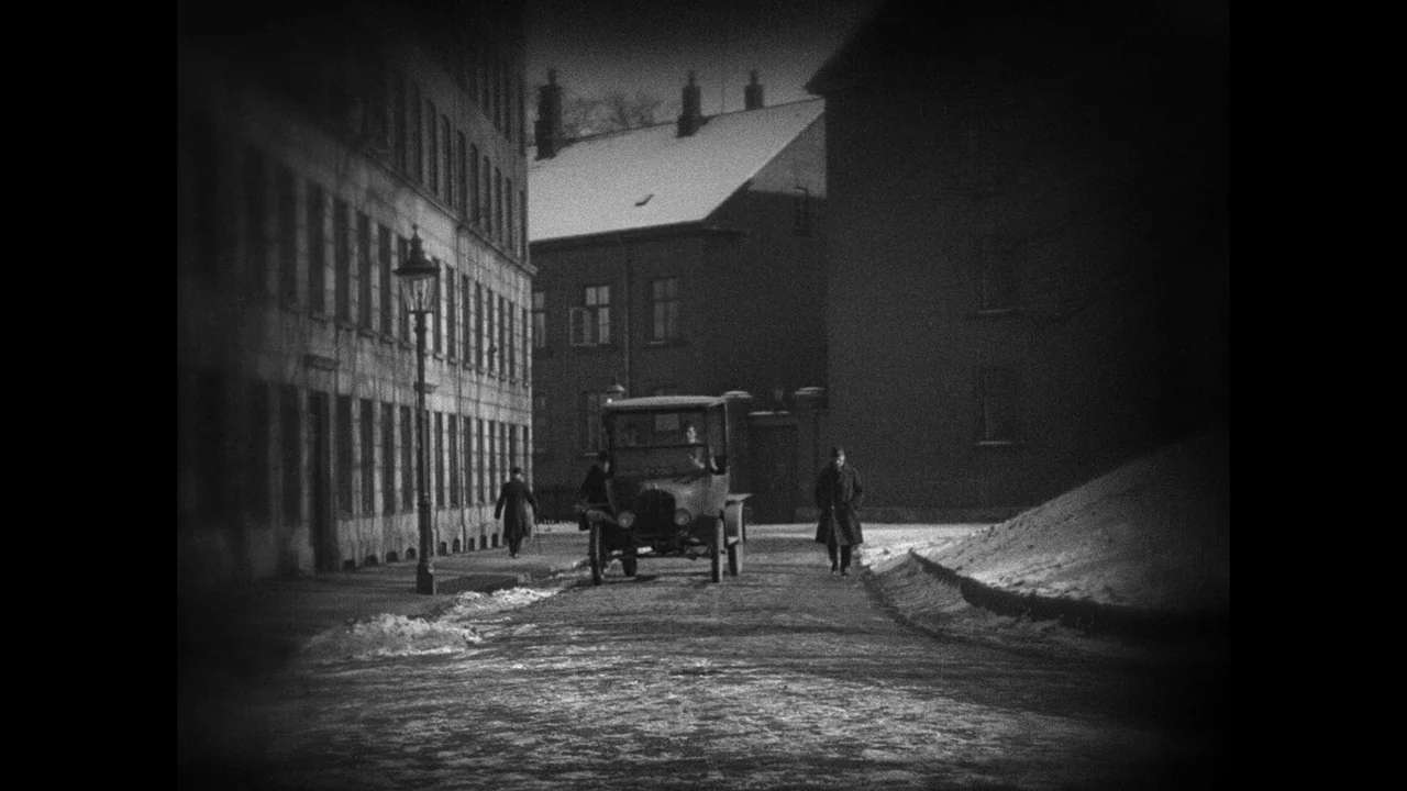 Master of the House (1925) movie still: wide — A quiet urban street lined with multi-story buildings covered in light winter snow. A vintage car…