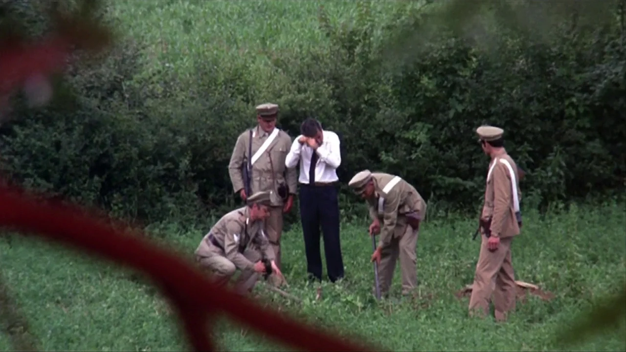 A Quiet Place In The Country (1968) movie still: wide — A group of men in military uniforms stand in a dense green field. They observe another man…