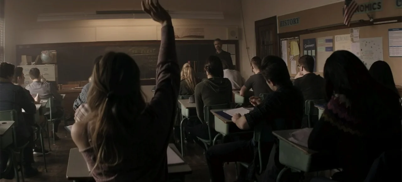 I Still See You (2018) movie still: medium — A high school classroom filled with rows of desks facing a front blackboard. A student in the…