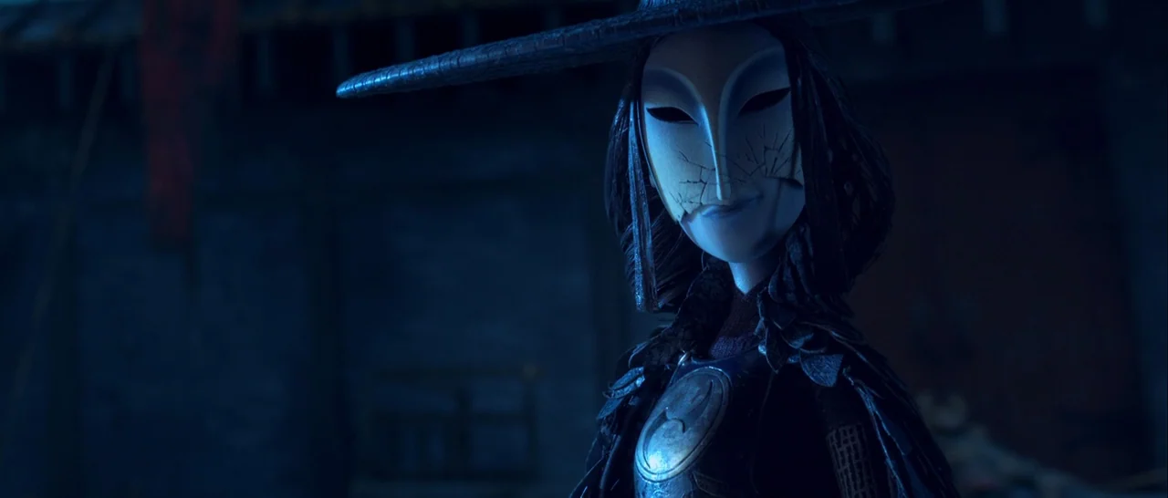 Kubo and the Two Strings movie still: closeup — A dimly lit room with blue ambient tones and textured dark walls. A figure in a cracked white mask…