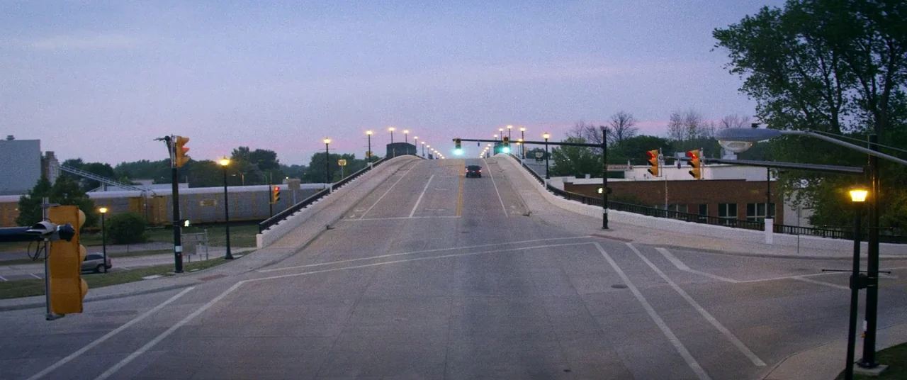 Kings Of Summer (2013) movie still: establishing — An empty concrete overpass rises into the distance under a dusk sky. One small vehicle drives…