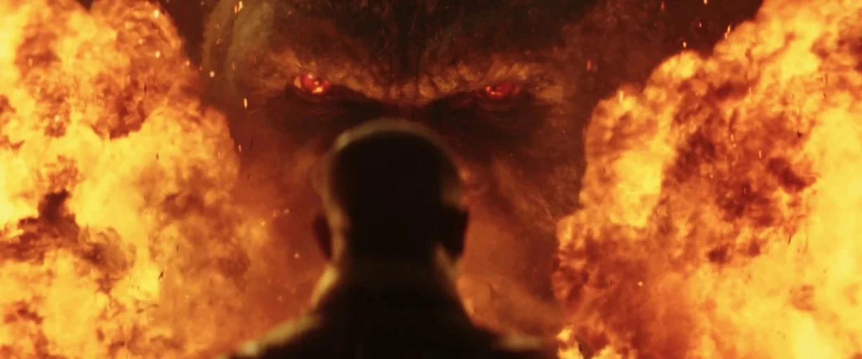 Godzilla: King of the Monsters (2019) movie still: medium — A dark environment is consumed by large bursts of orange flames and embers. A human…