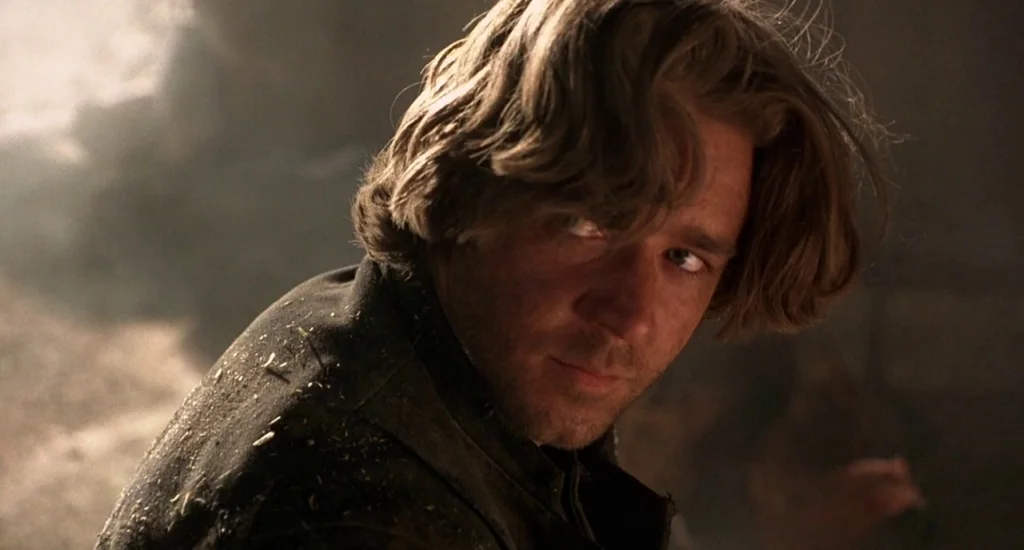 The Quick and the Dead (1995) movie still: closeup — A dimly lit room with stone walls and textured surfaces visible in the background. A man with…
