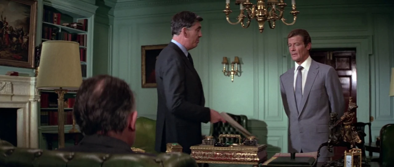 For Your Eyes Only (1981) movie still: medium — A formal office features sage green paneled walls, a chandelier, and antique desk accessories. A man…