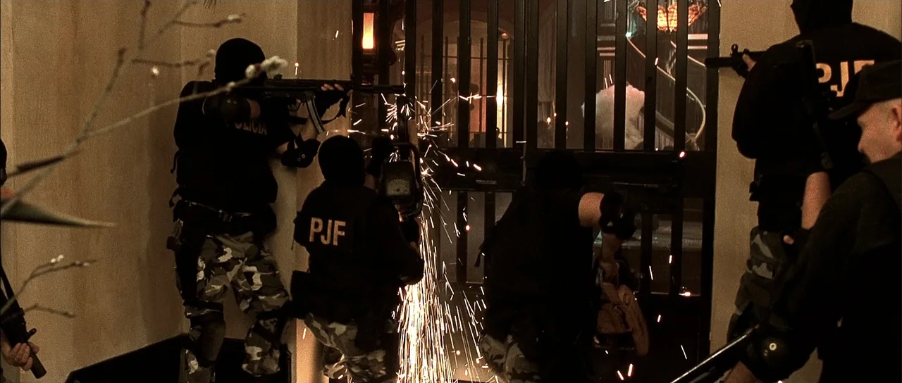 A Man Apart (2003) movie still: medium — A dark hallway features a heavy metal gate blocking a doorway. Four tactical officers in black vests and…