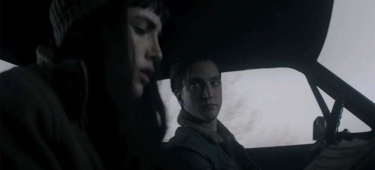 I Still See You (2018) movie still: medium — A dark vehicle interior with two people sitting in the front seats. A man drives while a woman sits…