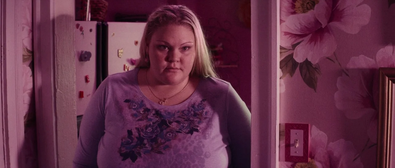 Dog Eat Dog (2016) movie still: medium — A woman stands in a domestic doorway flanked by floral-patterned wallpaper. She pauses in the passage while…