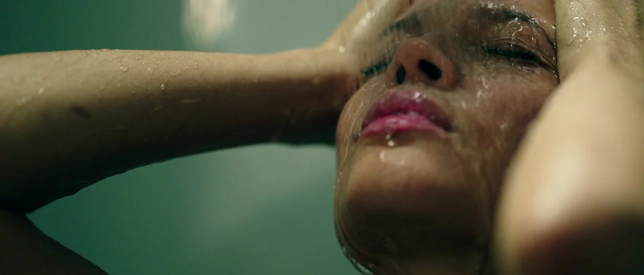 The Purge: Anarchy (2014) movie still: closeup — A dark bathroom setting provides a stark, muted background for a close-up shower scene. The subject…