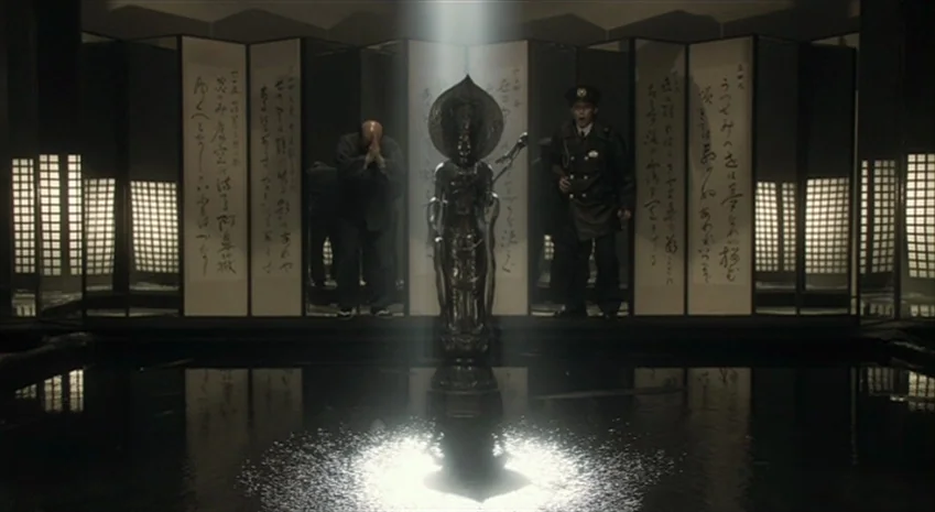 Rampo Noir (2005) movie still: wide — A dark space features a central reflecting pool with a metallic statue at its core. Traditional sliding screen…
