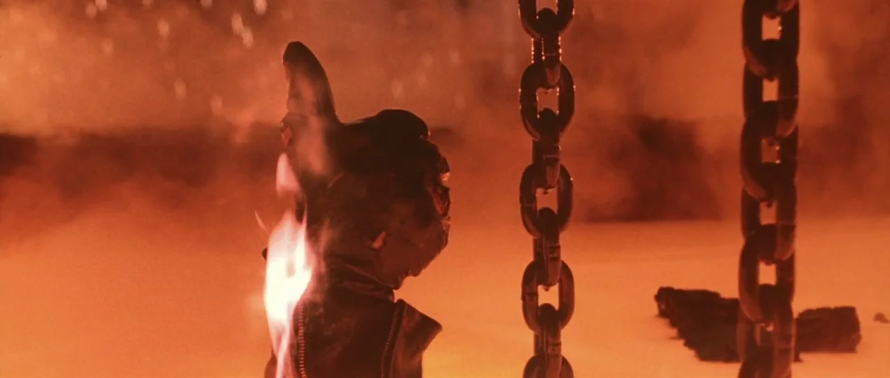 Terminator 2: Judgement Day (1991) movie still: medium — A robotic figure sinks into a pit of molten metal surrounded by thick orange smoke. Two…
