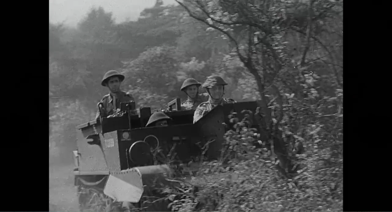 Made in England: The Films of Powell and Pressburger (2024) movie still: medium — A military vehicle moves through a dense rural area with trees and…