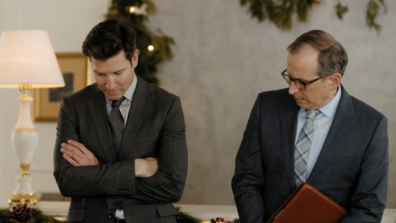 Christmas in Washington (2003) movie still: medium — A formal office space decorated with subtle holiday greenery in the background. Two men in…