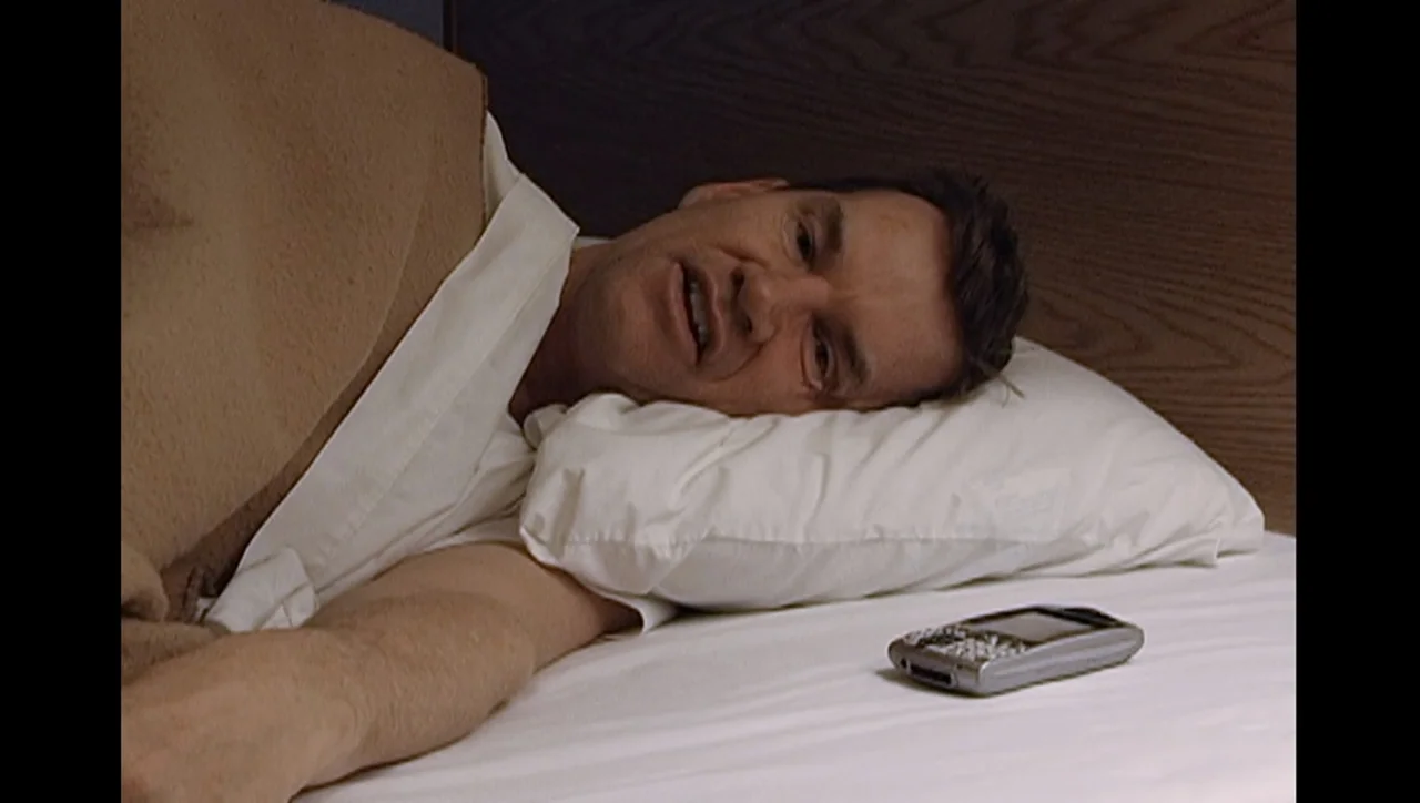 The Trials of Ted Haggard (2009) movie still: closeup — A man lies in a bed with white sheets and a beige blanket. He rests his head on a white…