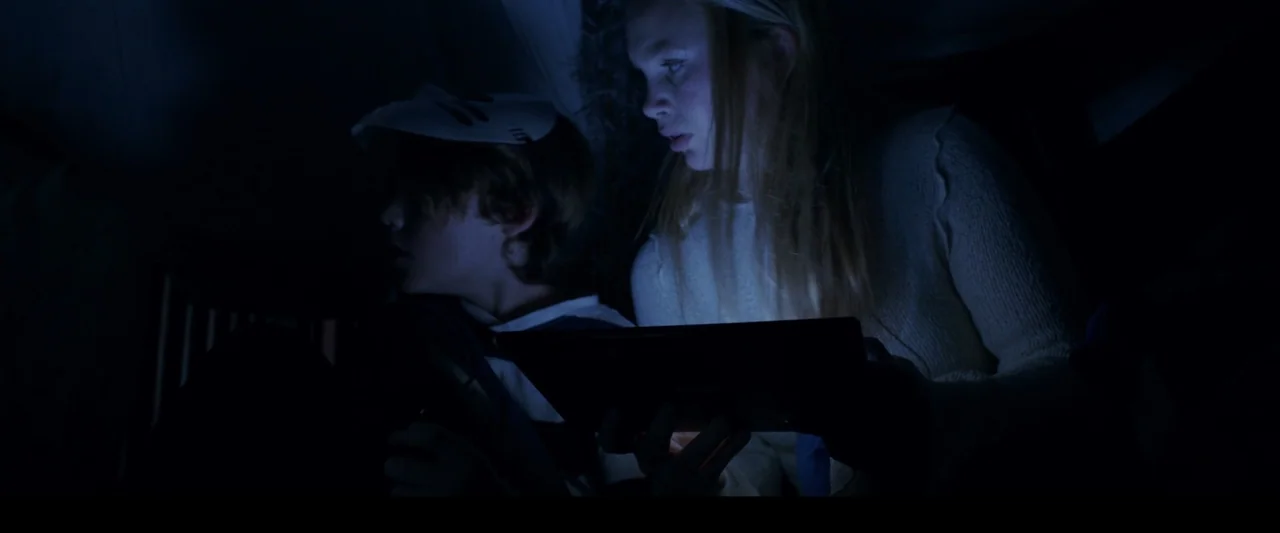 Winnie-the-Pooh: Blood and Honey 2 (2024) movie still: medium — Two adolescents sit in a darkened room illuminated by the glow of a mobile tablet.…
