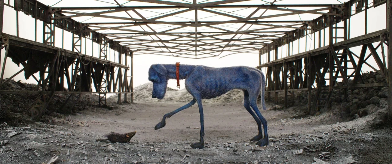 Isle of Dogs (2018) movie still: fullbody — A desolate wasteland with metal structures sits under a white, hazy sky. A blue canine puppet stands in…