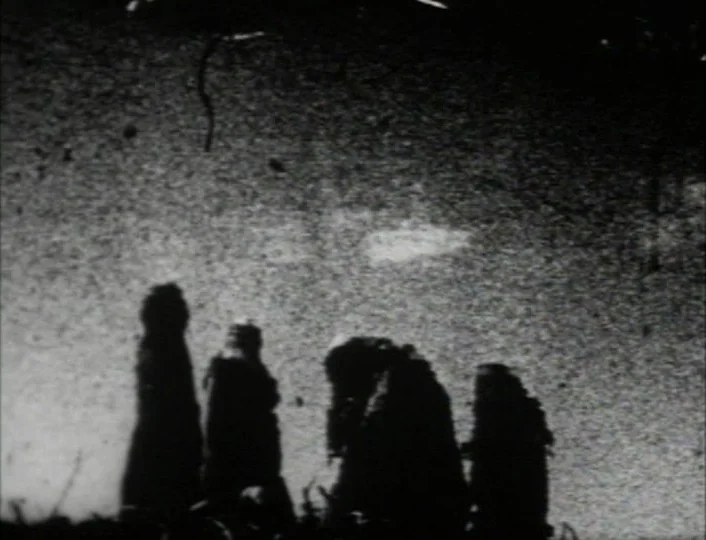 Begotten (1989) movie still: fullbody — Four figures in robes stand as silhouettes against a bright, grainy night sky. The subjects are arranged in…