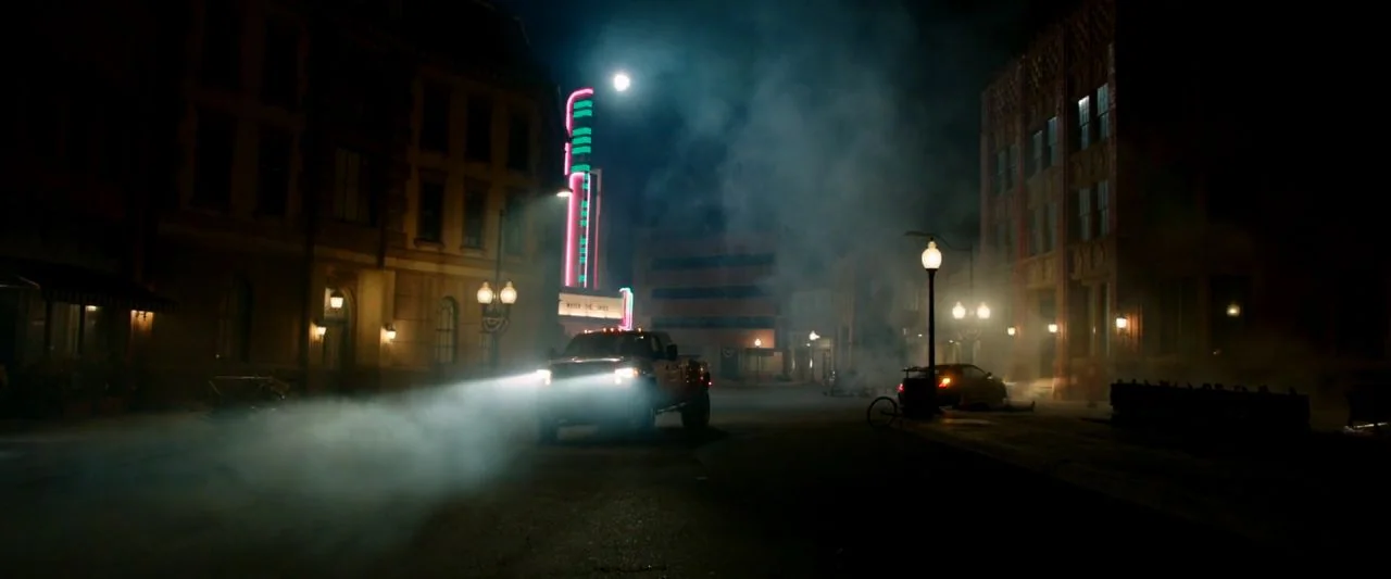 Cooties (2014) movie still: wide — A dark city street at night is filled with patches of thick low-hanging fog. A single pickup truck approaches…