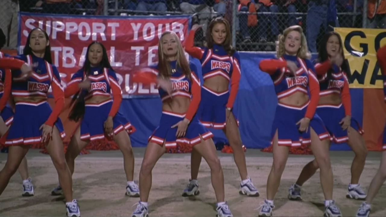 Not Another Teen Movie (2001) movie still: fullbody — A group of six cheerleaders perform on a dirt field at night. They wear identical blue and red…