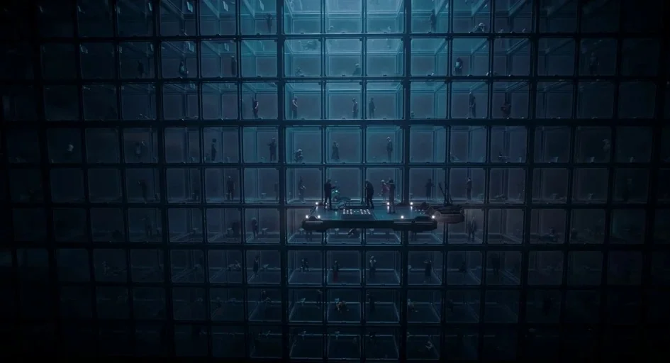 Superman (2025) movie still: establishing — A gargantuan structure consists of a grid of identical stacked transparent square cells. Tiny figures…