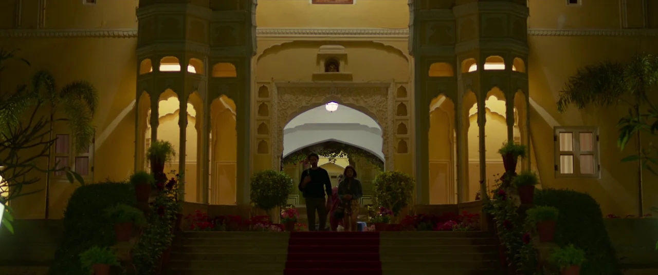 The Wedding Guest (2018) movie still: wide — An ornate yellow building features a grand entrance with traditional arched architectural details. Two…