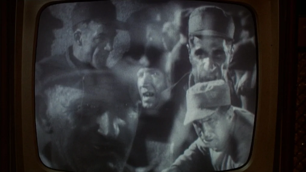 Targets (1968) movie still: medium — A grainy television screen shows several men wearing caps in a tight, crowded space. The black and white image…