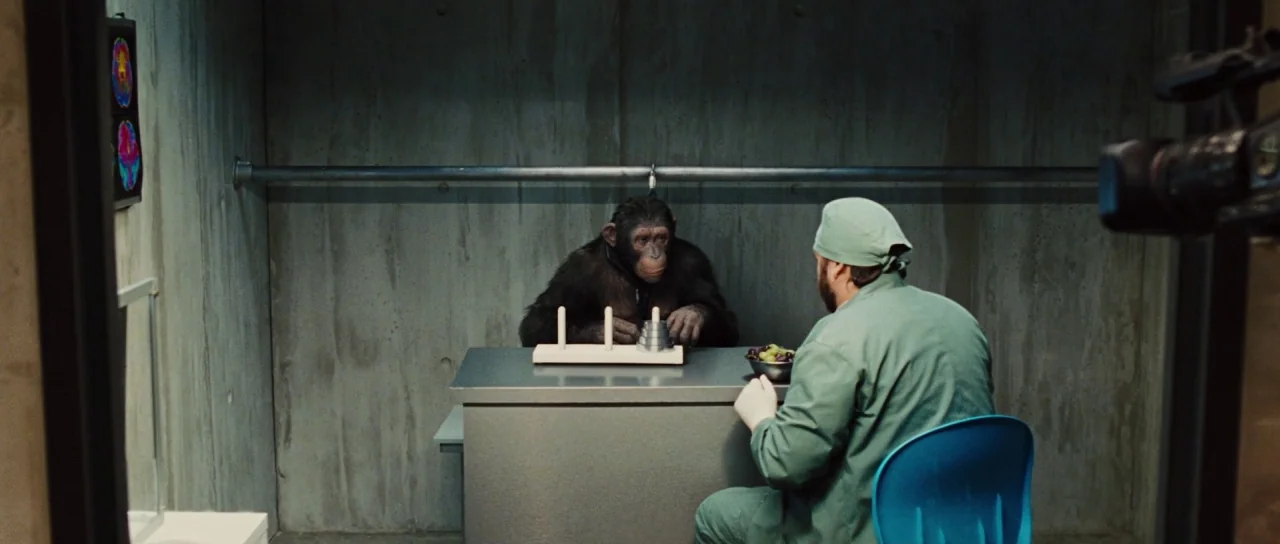 Rise of the Planet of the Apes (2011) movie still: wide — A utilitarian laboratory room with raw concrete walls and a gray metal desk inside. A…