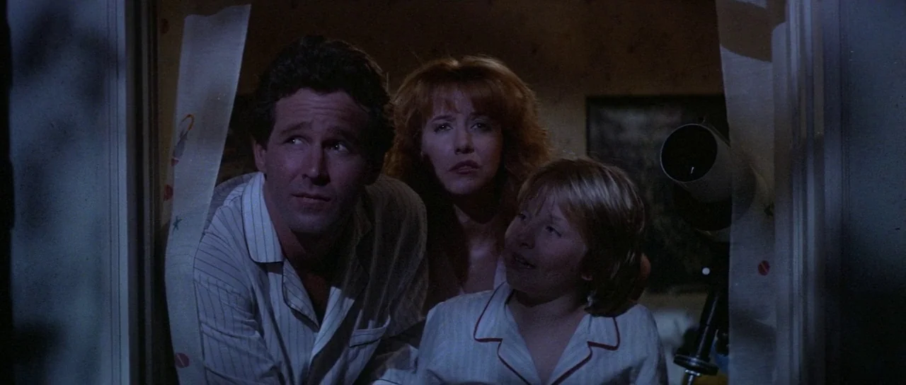 Invaders From Mars (1986) movie still: medium — A dark bedroom viewed through a doorway with light patterned curtains at the sides. A man, woman,…