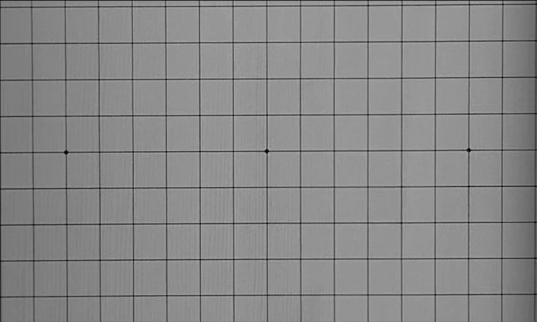 Pi (1998) movie still: establishing — A digital calibration grid appears on a flat surface with black lines. Three dark diamond markers are…